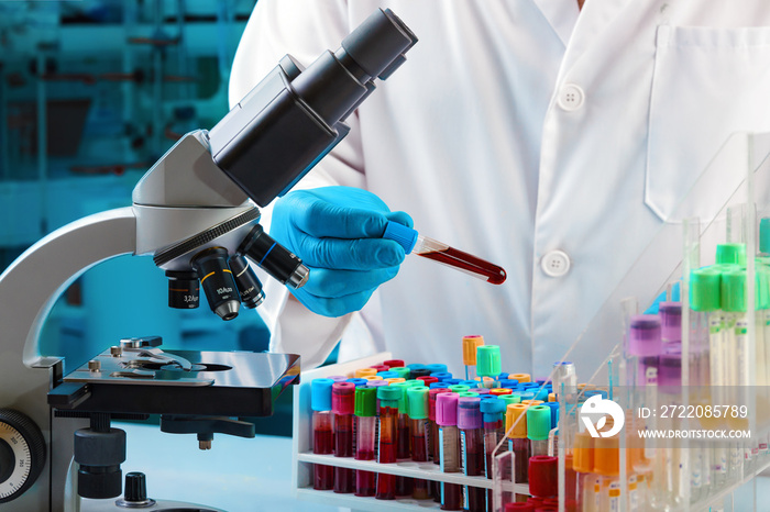 lab technician holding blood tube test for analysis in the microscope in the hospital laboratory / D