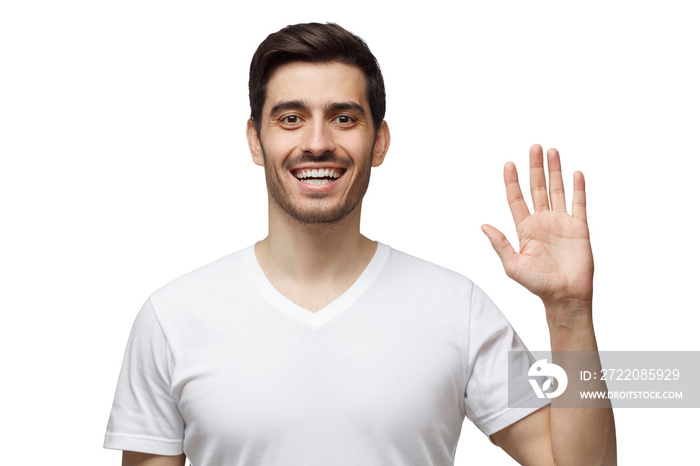 Hello! Hi! Young man greeting you with open hand, smiling, enjoying communication, isolated on white