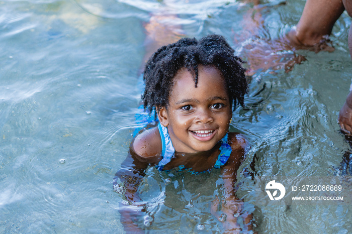 Retrato horizontal de una pequeña niña afroamericana de cabello afro muy sonriente y mirando a cámar