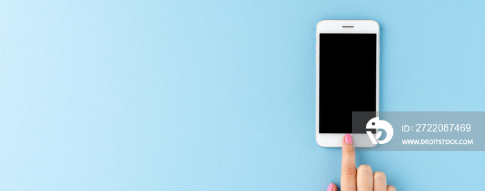 Woman’s hand using smart phone with empty screen on blue background. Banner