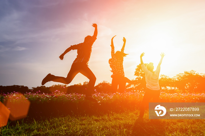 Silhouette of happy people jumping in sunset.