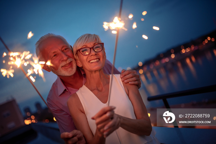 Happy senior couple celebrating with sparklers outdoor