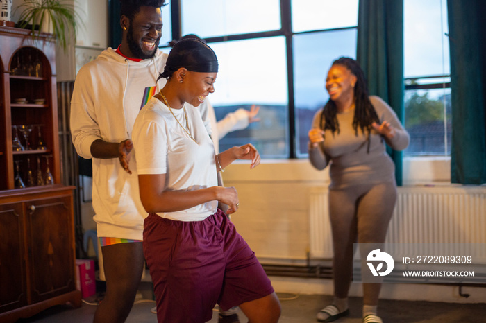 Friends laughing and dancing together in living room�