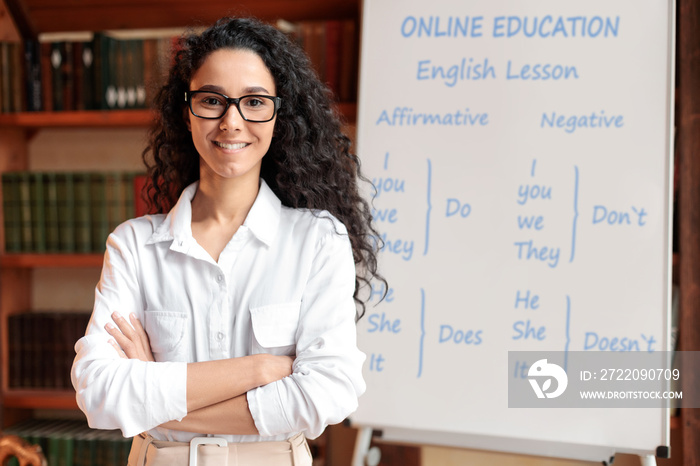 English teacher standing at board, posing at camera