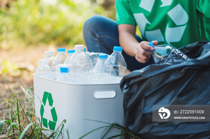 A woman picking up garbage plastic bottles into a box and bag for recycling concept