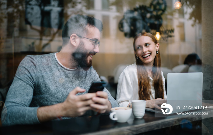 Cheerful couple using laptop in cafe