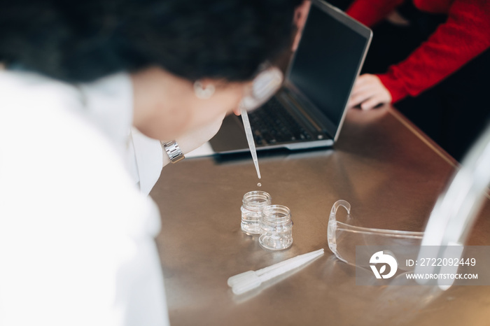 Female student adding solution in container during chemistry class at university