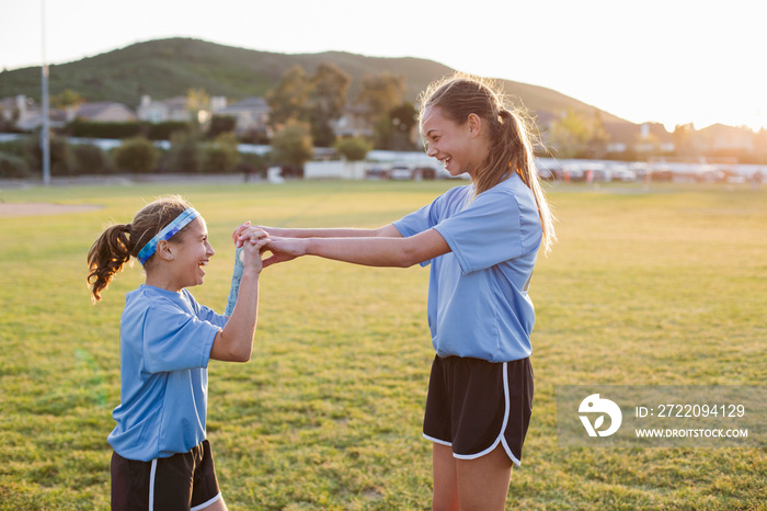 Cheerful friends holding hands in grassy field