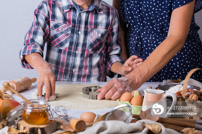 Grandmother with grandson cooking, kneading dough, baking in the kitchen