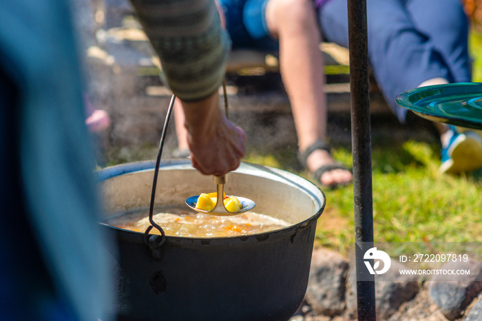 Cooking food in a pot on campfire. Summer camping concept.