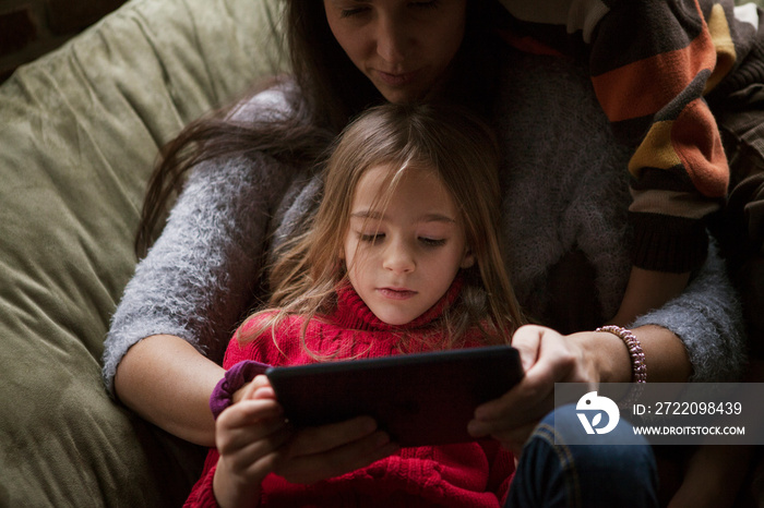 Mother and daughter using digital tablet on beanbag