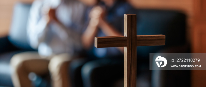 Close up cross is blur background. Asian Christian woman and man holding hands in praying for Jesus’ blessings to show love and confession of their sins according. Concept giving love faith..