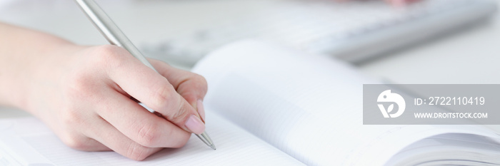 Female hand holding silver pen ready to make note in opened notebook sheet. Businesswoman in suit at workspace make thoughts records at personal organizer, white collar conference, signature concept