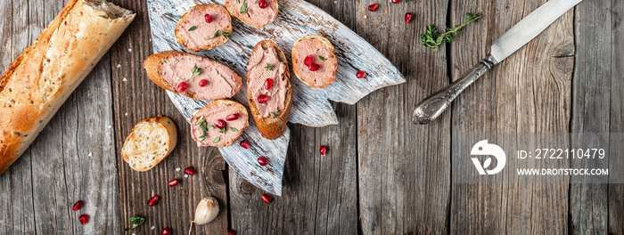 gourmet Belgian duck liver pate bread on a wooden background. Fresh homemade chicken liver pate on toasted bread with greens and pomegranate. Long banner format. top view. place for text