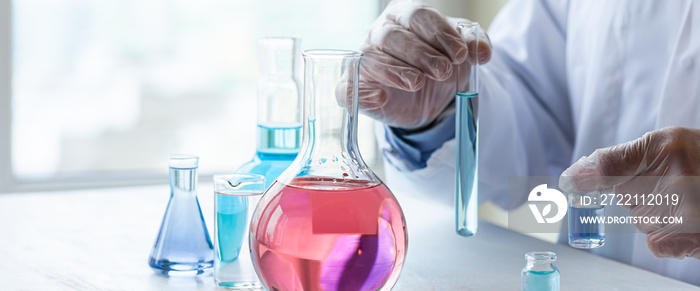 Young man scientist in glasses and gloves working on laboratory test of blue liquid in tube, chemistry science, medical biology experiment technology, pharmacy development solution. Close up banner