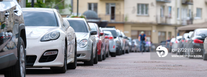 Cars parked in line on city street side. Urban traffic concept