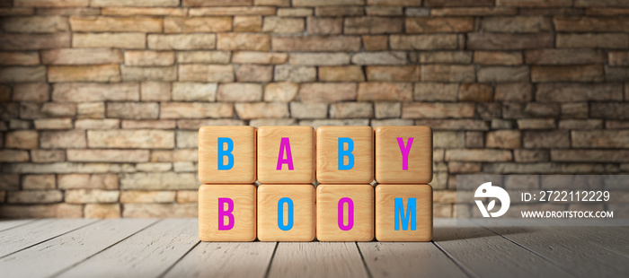 Baby Boom concept with pink and blue letters for girls and boys on wooden cubes in front of a brick wall with copyspace and vignette