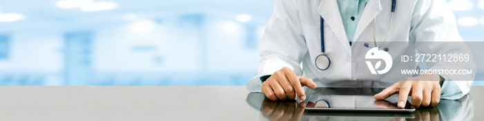 Male doctor sitting at table with tablet computer in hospital office. Medical healthcare staff and doctor service.