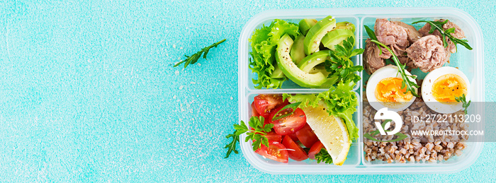 Healthy food. Lunch- Buckwheat porridge, sliced tuna, boiled egg and fresh vegetable salad in container  on blue background. Top view, banner