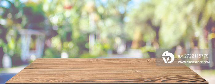 spring background.Empty brown wooden table with blur tropical  tree in garden boekh background,banner mockup template for display of product