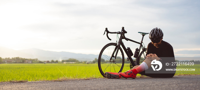 Bike injuries. Man cyclist fell fell off road bike while cycling. Bicycle accident, injured knee. Road in Thailand.