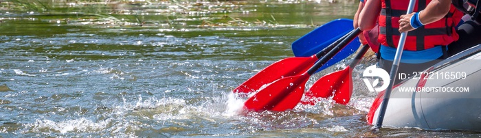 Rafting trip. Close up view of oars with splashes of water. Rowers make an effort to overcome the turbulent river. The concept of teamwork, healthy lifestyle.