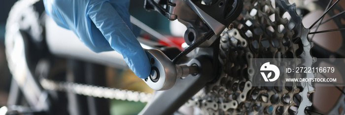 Handyman in rubber gloves repairing bicycle in workshop closeup