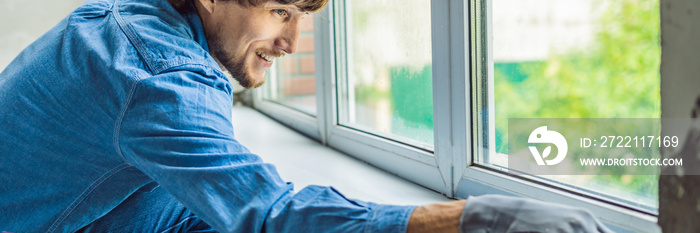 Man in a blue shirt does window installation BANNER, long format