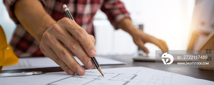 Close up hand of architect working and checking on blue print and laptop, designer and engineer work in office