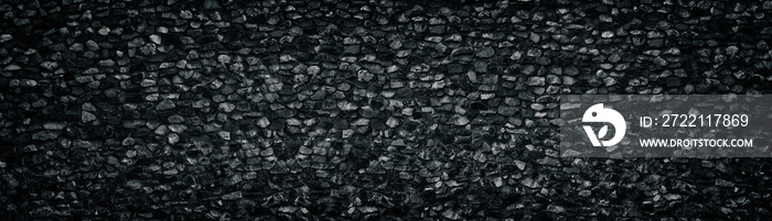 Black crushed granite stone wall wide texture. Angular rock surface panorama. Dark panoramic background