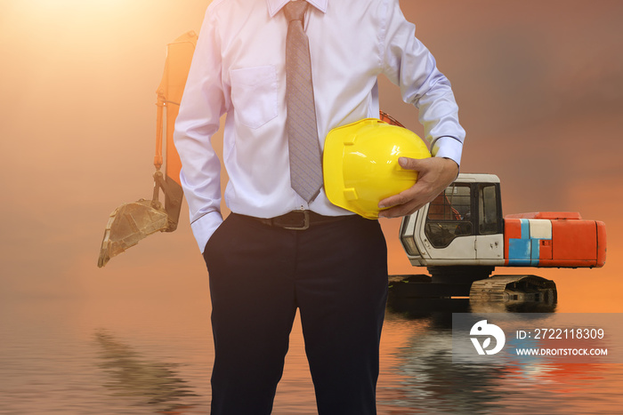 Safety Construction Concept , Safety engineer holding yellow hardhat and Loader  backhoe  truck background.