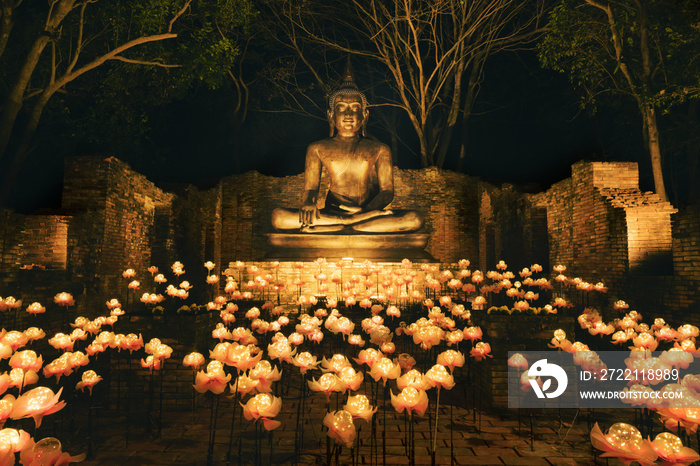 sitting bronze Buddha statue at night with lighting decoration