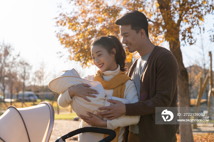 年轻夫妻推着婴儿车散步