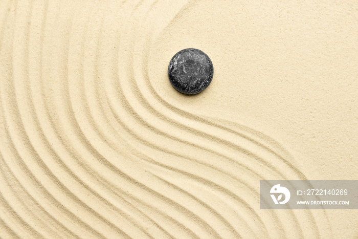 Black spa stone on light sand