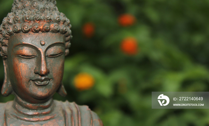 Buddha Statue in Garden with blurred flowers in background