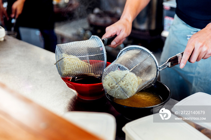 Chef boiling ramen noodle in soup for making miso and shoyu ramen.