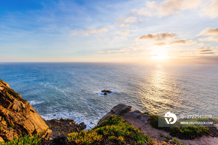 beautiful view of the ocean from rocky mountains. reflection of the sun on the water and a line of horizon that separates blue sky with clouds and blue water of the ocean