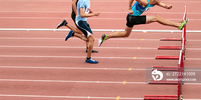 race men athletes run 110 meters hurdles in athletics competition