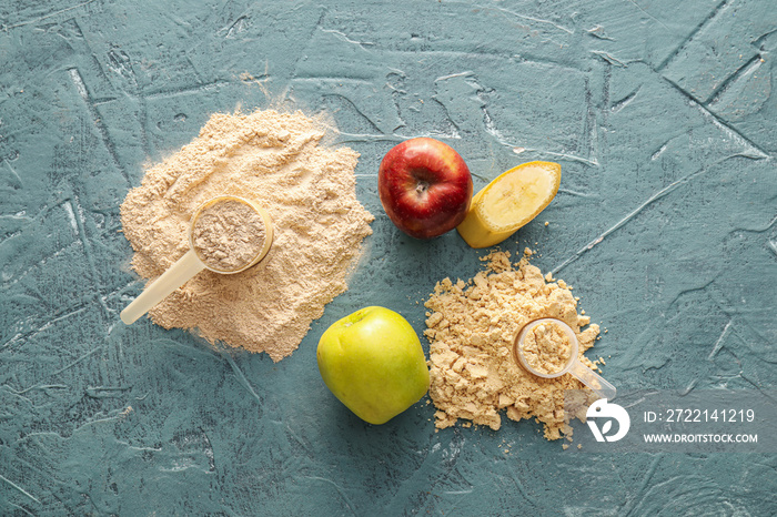 Measuring scoops with protein powder, apples and banana on color background