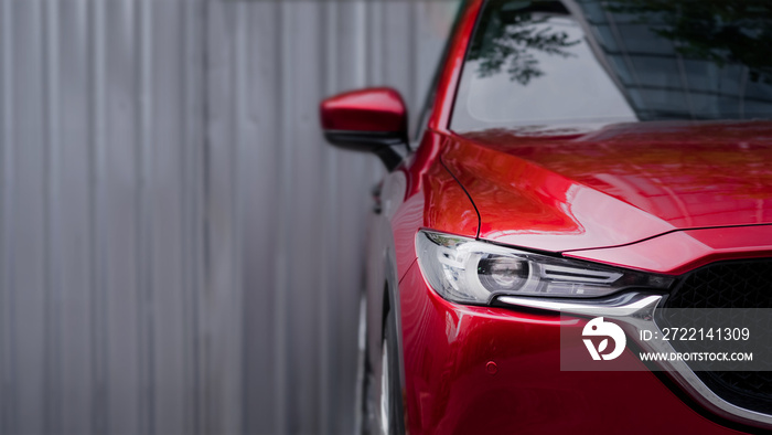 close up headlight of red car against gray blurred background.