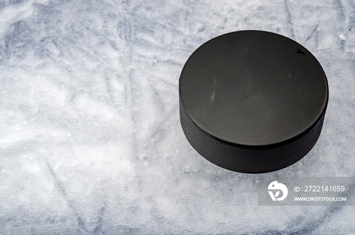 Sports equipment and team winter sport concept with closeup on hokey puck on ice rink with copy space