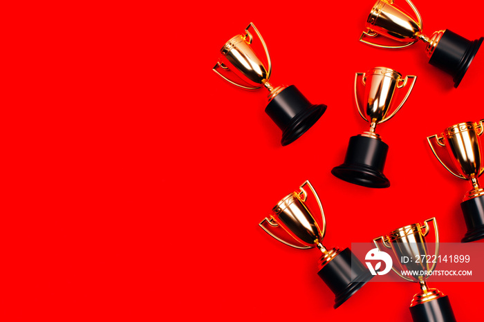 Winner cups on a red background with copy space. Flat lay style.