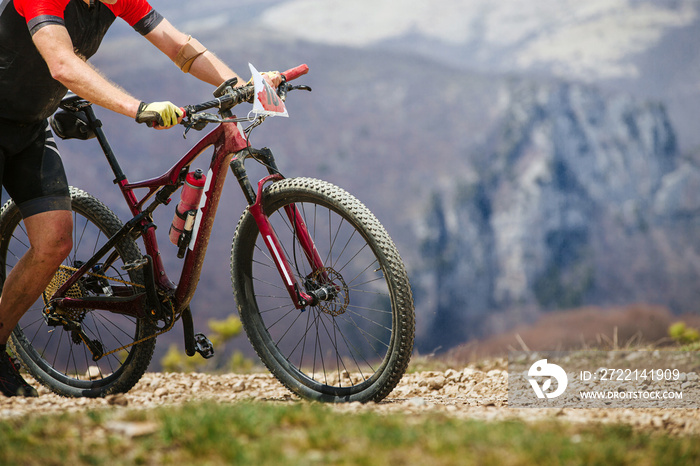 athlete walking with his mountainbike hard climb uphill