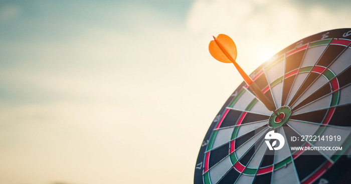 Close up shot of the dart arrow hit on bulleyes of dartboard to represent that the business reached the target  with dark tone picture style. Target and goal as concept.