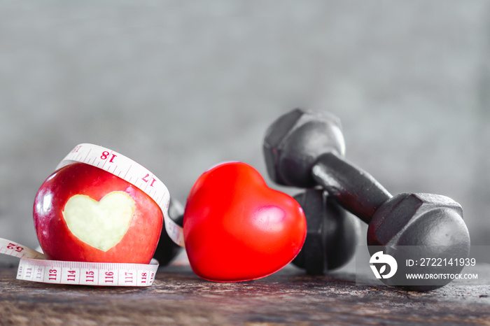 red apple with dumbbells ,measuring tape, sport diet and heart healthy concept