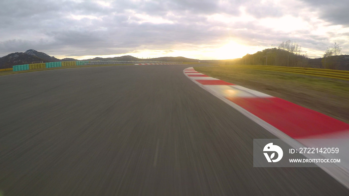 POV: Racing a car down the empty asphalt circuit on a beautiful golden evening.