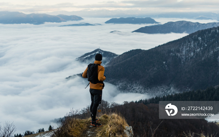 Hiker with backpack reaches the summit of mountain peak during winter.  Success, freedom and happiness, achievement in mountains. Active sport concept.