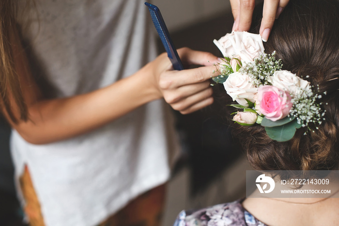 Hair stylist makes the bride a wedding hairstyle with fresh flow