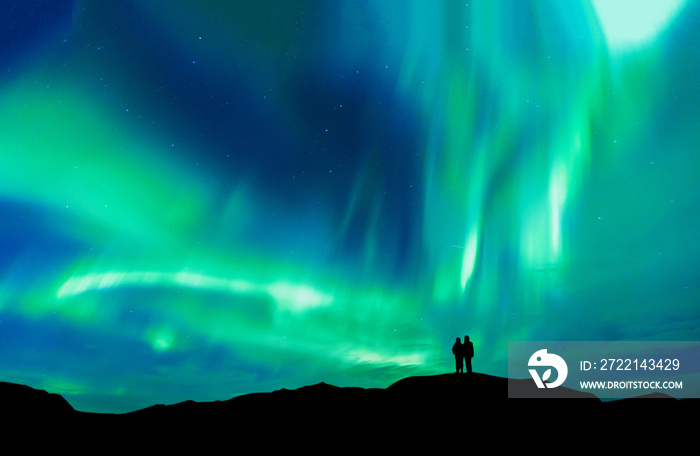 Aurora borealis with silhouette love romantic couple on the mountain.Honeymoon travel concept