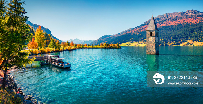 Panoramic autumn view of Tower of sunken church in Resia lake. Sunny morning scene of Italian Alps, South Tyrol, Italy, Europe. Traveling concept background.